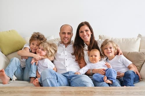 Familia con varios niños sentada junta en un sofá