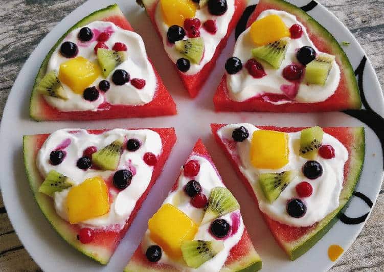 Vannmelonskiver dekorert med yoghurt og frukt, formet som små pizzaer