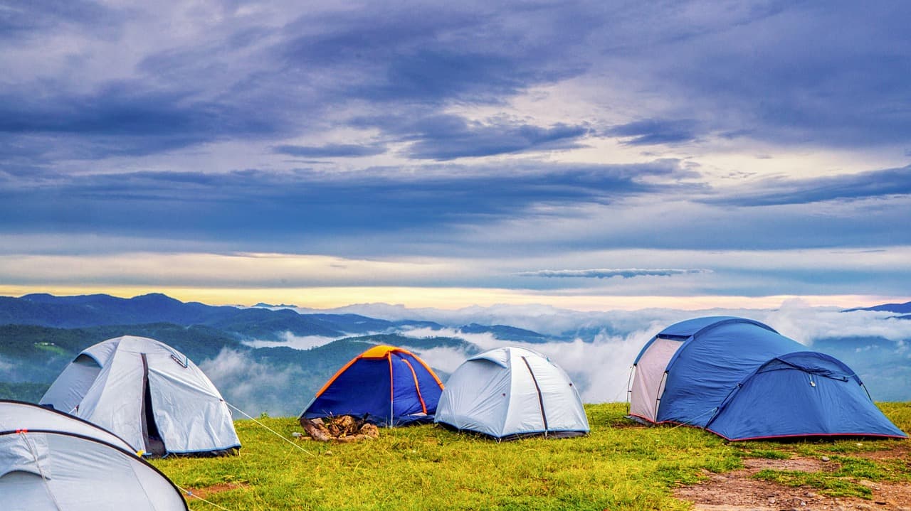 Tiendas de campaña en un camping al amanecer con montañas al fondo