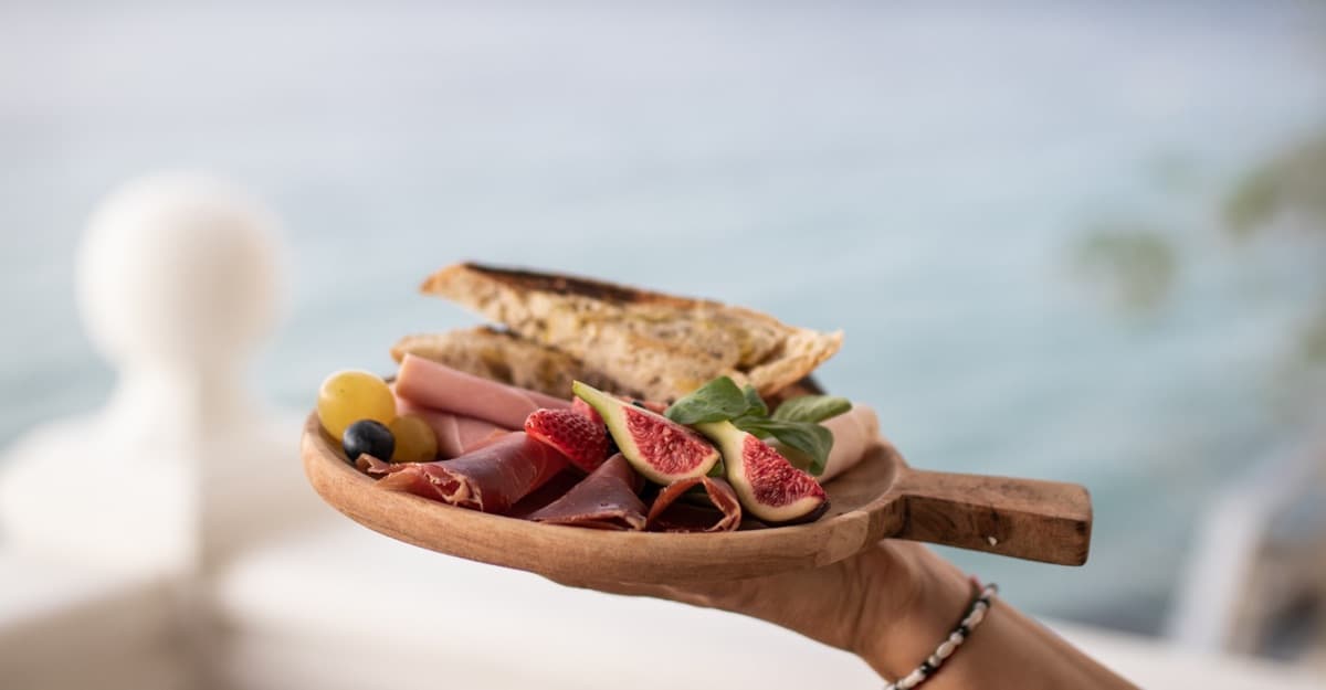 Tabla de desayuno con jamón, higos y tostada frente al mar en D·Vora